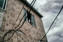 homem usando máscara apoiado na janela 