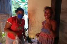 Mulheres negras entregando alimentos uma a outra