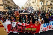 Manifestação do Dia de Ação Global em Glasgow, na Escócia. Na frente, vemos lideranças indígenas do Brasil com cartazes coloridos que chamam a atenção para as ações contra a mudança climática.