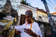 Mulher jovem negra segura documento em área histórica do Rio de Janeiro