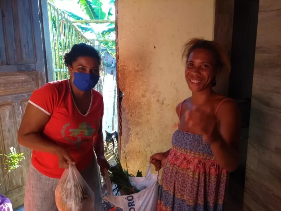 Mulheres negras entregando alimentos uma a outra