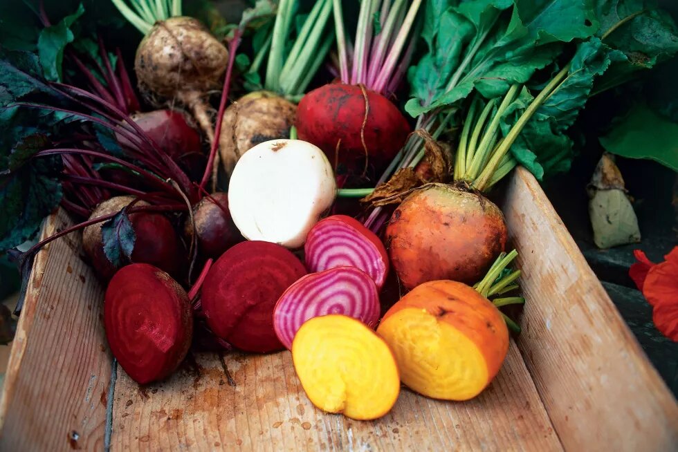 Legumes frescos cortados e inteiros em um caixote de madeira