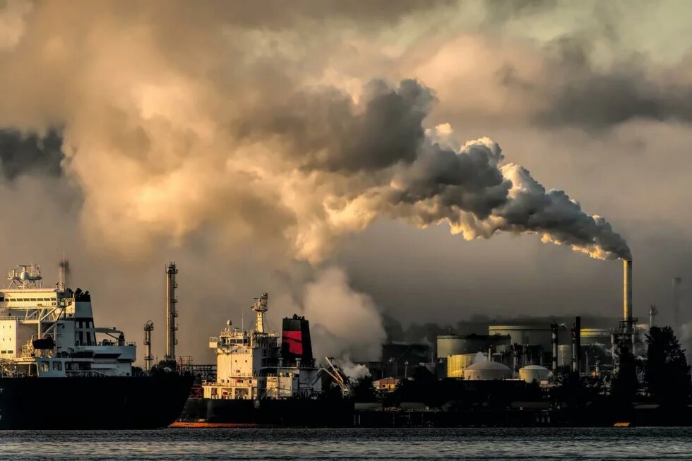 Imagem de gases sendo lançados na atmosfera em uma Indústria próxima ao litoral.