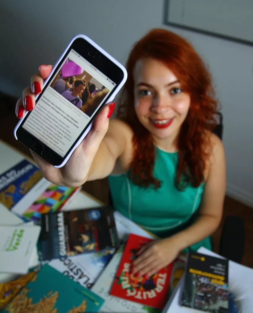 Vaga de estágio da Böll Brasil Jovem com celular na mão anunciando conteúdos da Fundação