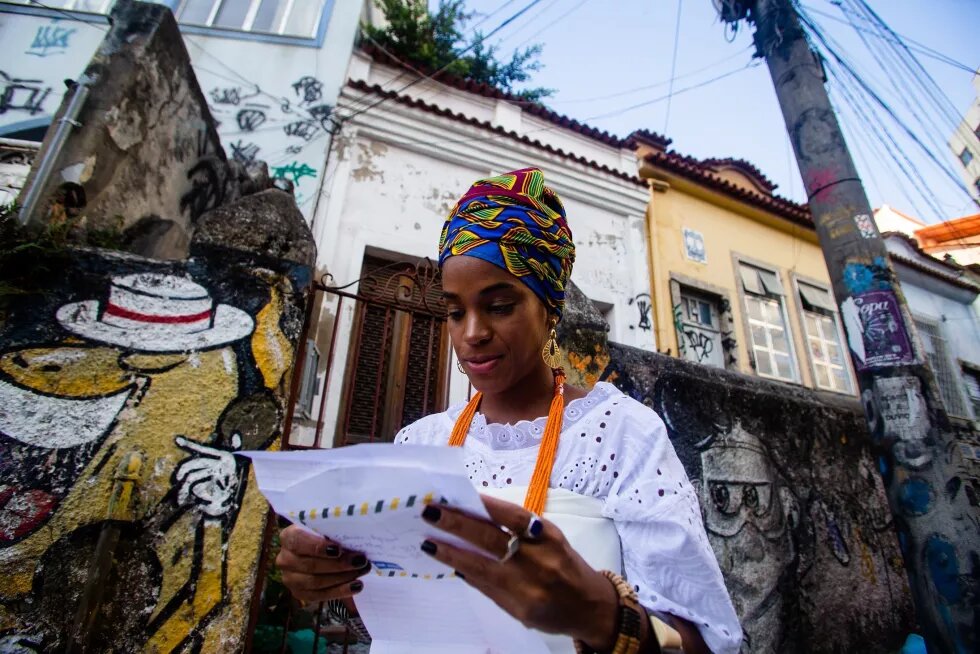 Mulher jovem negra segura documento em área histórica do Rio de Janeiro